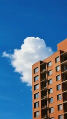 Fototapeta premium Modern Apartment Building Against a Clear Blue Sky with a Single Cloud