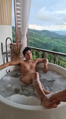 Handsome Man Unwinding in Bubble Bath with Stunning Mountain View at Twilight