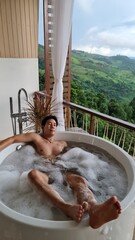 Handsome Man Unwinding in Bubble Bath with Stunning Mountain View at Twilight
