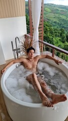 Handsome Man Unwinding in Bubble Bath with Stunning Mountain View at Twilight