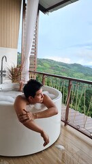Handsome Man Unwinding in Bubble Bath with Stunning Mountain View at Twilight