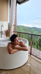 Handsome Man Unwinding in Bubble Bath with Stunning Mountain View at Twilight