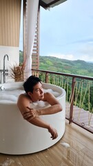 Handsome Man Unwinding in Bubble Bath with Stunning Mountain View at Twilight