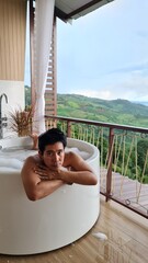 Handsome Man Unwinding in Bubble Bath with Stunning Mountain View at Twilight
