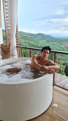 Handsome Man Unwinding in Bubble Bath with Stunning Mountain View at Twilight