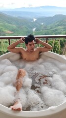 Handsome Man Unwinding in Bubble Bath with Stunning Mountain View at Twilight