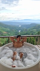 Handsome Man Unwinding in Bubble Bath with Stunning Mountain View at Twilight