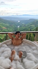 Handsome Man Unwinding in Bubble Bath with Stunning Mountain View at Twilight