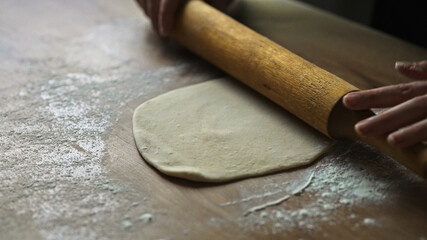 Rolling dough with wooden rolling pin kitchen.