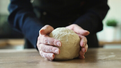 Kneading dough by hand on kitchen counter.