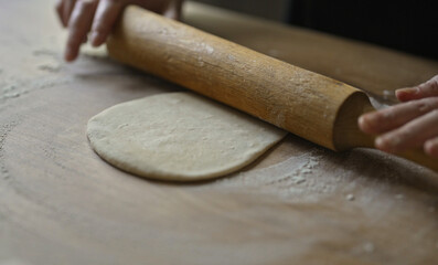 Rolling dough with wooden rolling pin kitchen.