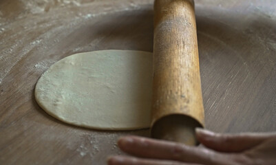 Rolling dough with wooden rolling pin kitchen.