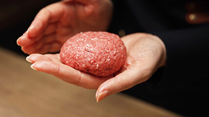 Preparing beef patty with salt and mixing.