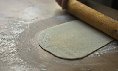 Rolling dough with wooden rolling pin kitchen.