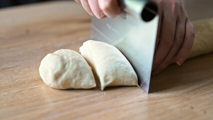 Cutting rolled dough with metal dough scraper.