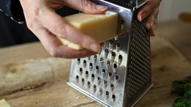 Grating hard cheese on metal kitchen grater.