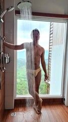 Handsome Man Showering with Panoramic Window View of Lush Green Mountain Valley