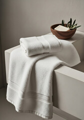 Soft white bath towels folded neatly with a small bowl of soap and olive branches