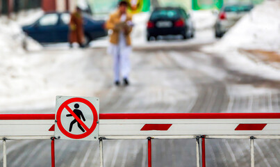 Traffic barrier blocking pedestrian access while icy streets shimmer under soft winter sunlight
