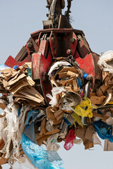 Excavator Grapple Holding Cardboard and Plastic Waste – Industrial Recycling and Environmental...