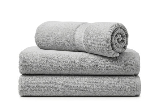 Stack of three soft grey bath towels rolled and folded neatly