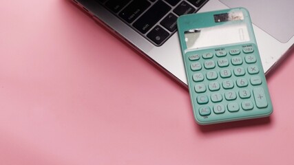 calculator and laptop on pink background