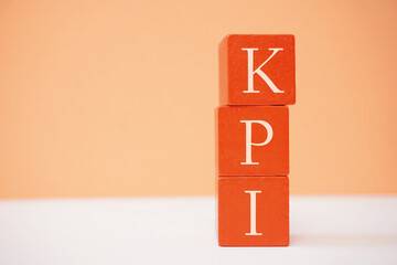 Stacked orange blocks displaying the acronym KPI on a peach background signifying business...