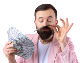 Portrait of a contented young businessman with a beard dressed in a pink jacket showing us dollar banknotes against a red studio background. Taste, smell of money.