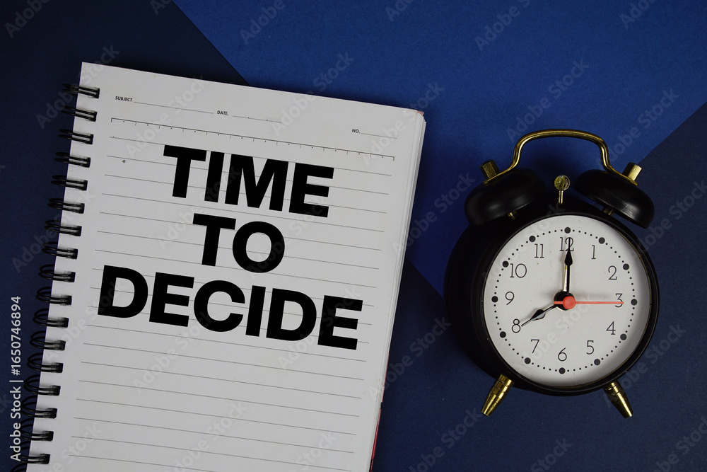 Poster time to decide text written on notepad with alarm clock on blue background