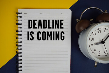 Deadline is Coming text written on notepad with alarm clock on yellow background