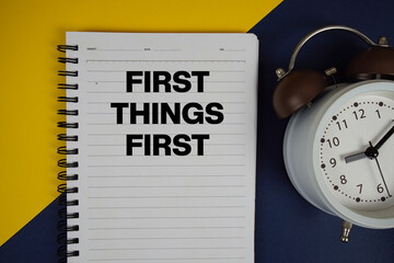 First Things First text written on notepad with alarm clock on yellow background