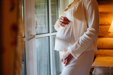 pregnant woman in white pajamas by the window. 