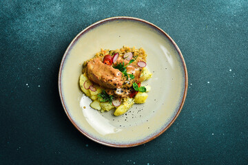 Stewed pork ribs in a cream sauce, with boiled potatoes. On a plate. Restaurant serving. Close up. On a dark stone background.