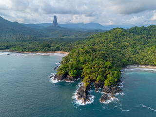 Tropical coastline of São Tomé with lush jungle, rocky cliffs, and the iconic Pico Cão Grande in...