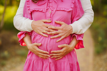 A man holds on to the tummy of a pregnant woman with his hands. 