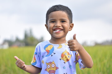3 year old Asian child with a cheerful face and thumbs up