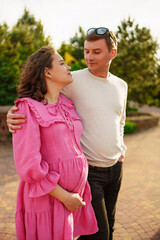 Man gently hugging pregnant woman while sitting in garden at home. 
