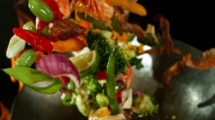 Super Slow Motion of Flying Asian Meal with Vegetable and Meat.Filmed on High Speed Cinema Camera, 600 fps. Isolated on Black Background, Flames Burning Around. - Powered by Adobe