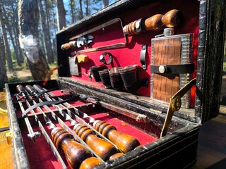 set of steel barbecue tools with wooden handles in a black rectangular case with red lining