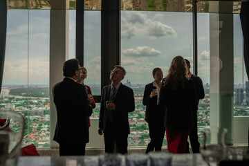 Informal networking session at a rooftop hotel cocktail lounge, with executives relaxing and...