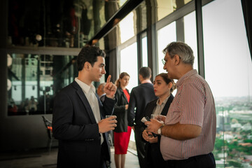 Rooftop hotel reception with executives building relationships over drinks, set against a city...