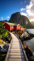Fototapeta premium Wooden path leads to red houses on a rocky coast near a mountain, bathed in sunlight