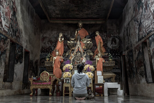 Young woman sitting praying pay respect to Buddha statue in the .Wat Kongkharam Rajavaravihara (Photharam). Worship pray.