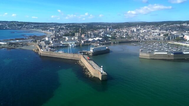 Penzance, Cornwall, England: DRONE VIEWS: The drone circles Penzance harbour showing the lighthouse, town and coastline. Penzance is a popular UK holiday destination (Clip 1 of 5).