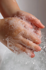 Fototapeta premium close up of little girls hands being washed with soap under running water on white background,
