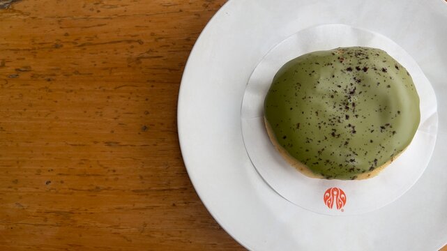 Sleman, Indonesia - August 15tb 2025: J.Co Green tea donut on a white plate above brown wooden table