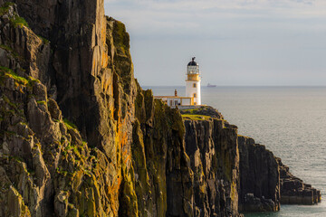 Widok na latarnię na Neist Point o zachodzie słońca, ze statkiem w tle.