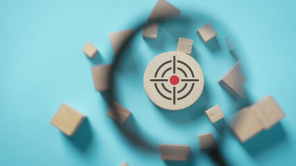 Target symbol on wooden block under magnifying glass, concept of business focus, goal setting,...