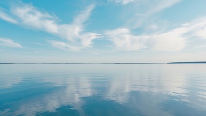 Wide view of a calm lake with a partly cloudy sky, reflecting on the water's surface.