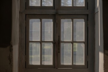 Vintage multi-pane window framing a softly blurred garden scene with diffused sunlight creating an serene, nostalgic atmosphere